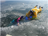 Firefighter practices ice rescue techniques with a child-size mannequin at a winter training drill.